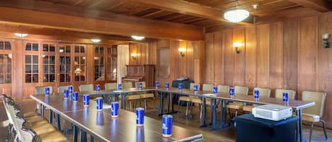 A conference room with long tables, chairs, and a projector on a table.