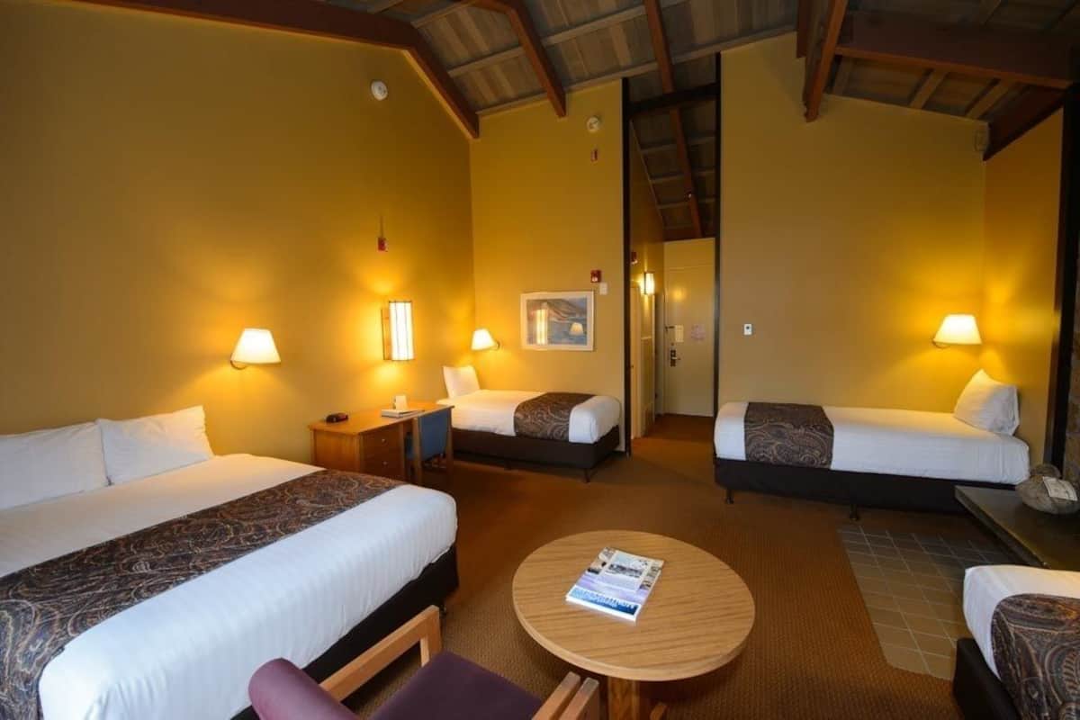A hotel room with two beds, a round table, and a small sitting area.