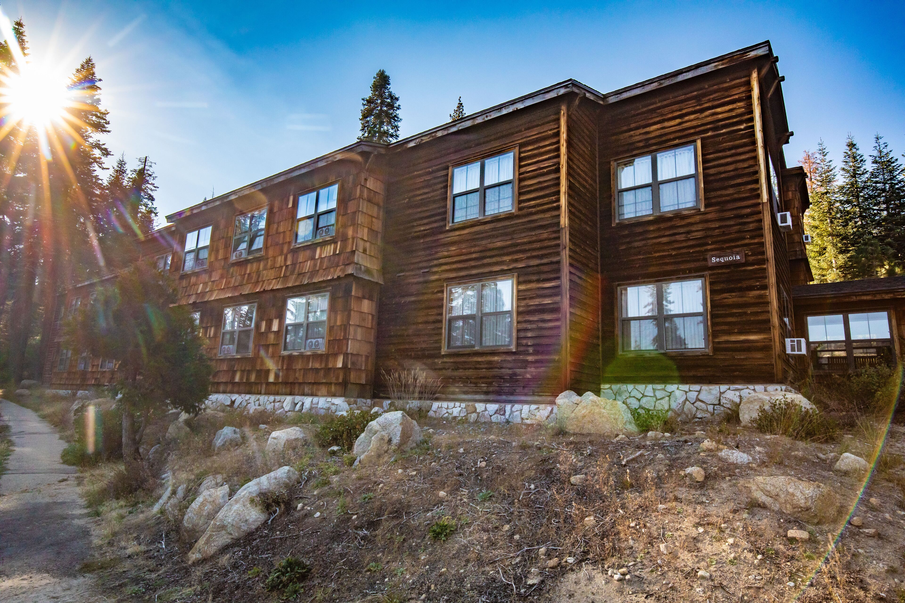 A two-story wooden cabin with multiple windows and a stone foundation.