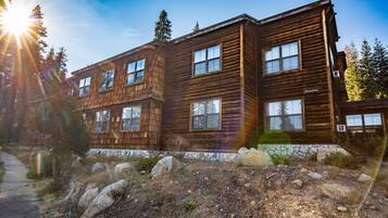 A two-story wooden cabin with multiple windows and a stone foundation.