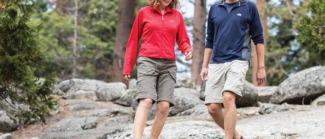 Two people walking on a rocky path surrounded by trees.