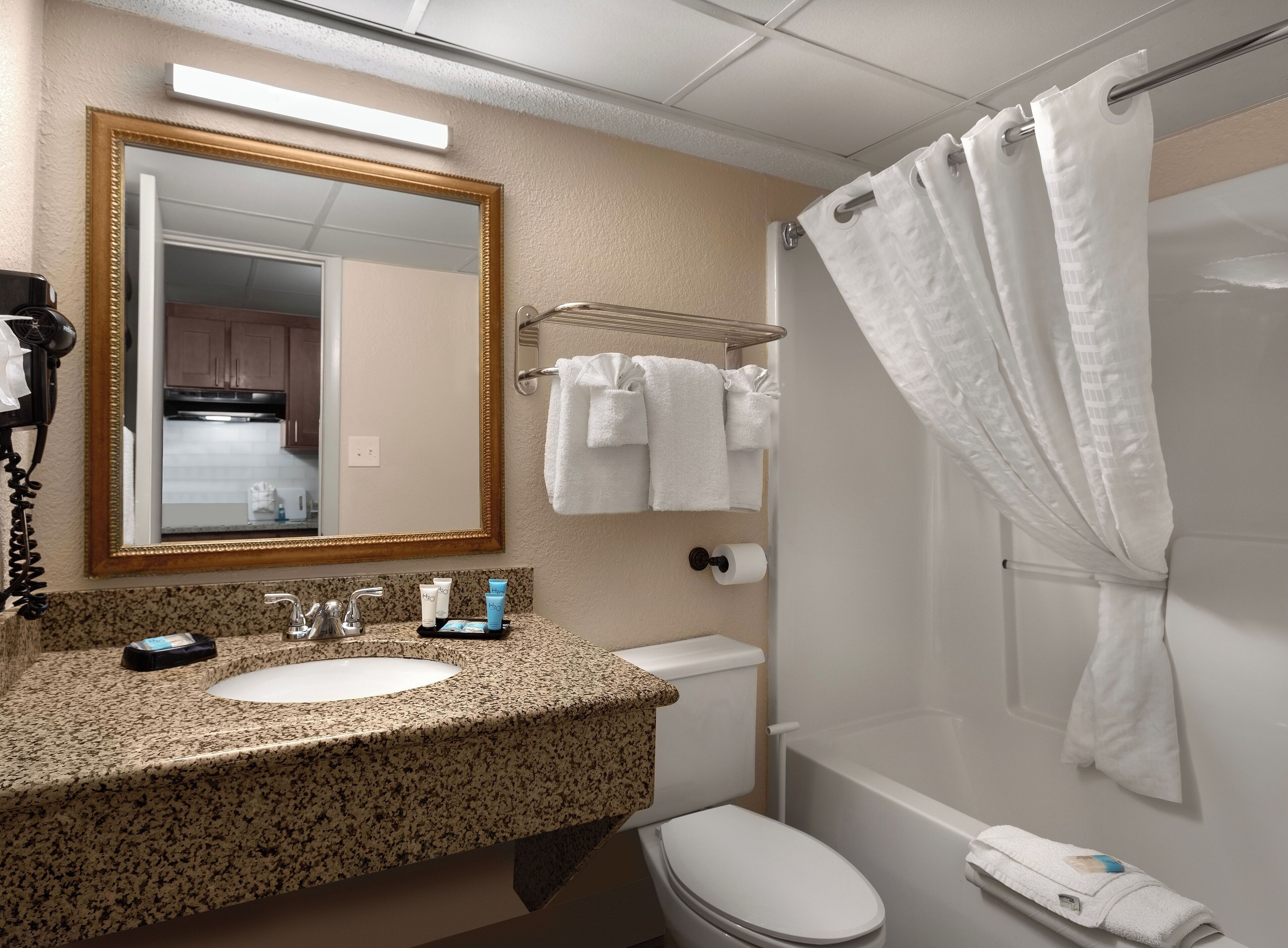 A bathroom with a sink, mirror, toilet, and shower.