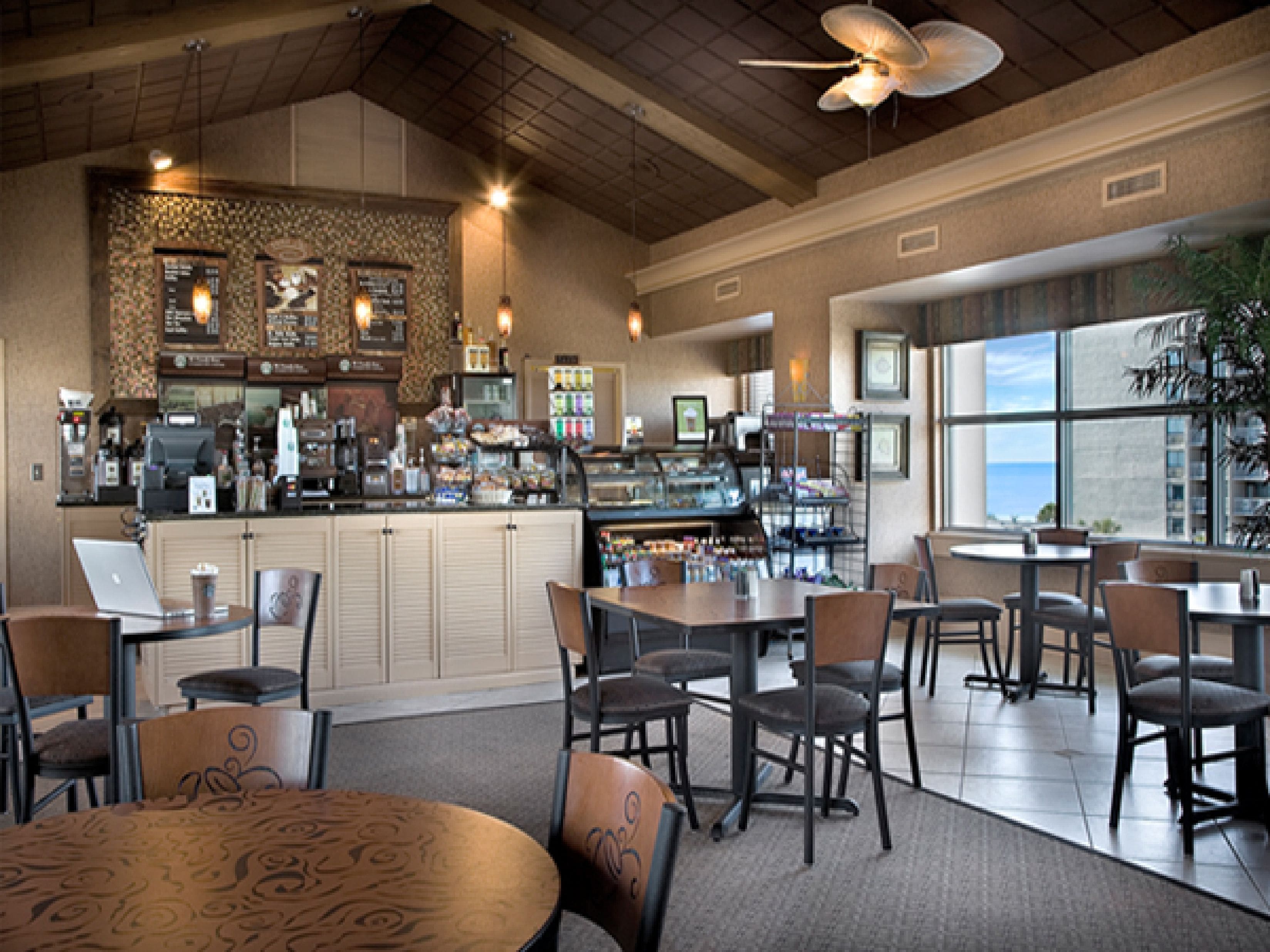 A restaurant with a bar area, seating, and a view of the city.