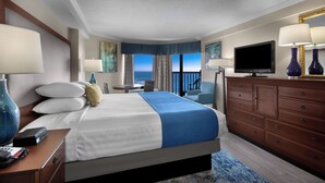 Una camera d'albergo con un letto, una TV, un comodino e vista sull'oceano.