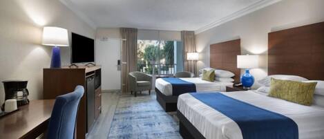 A hotel room with two beds, a desk with a chair, a television, and a view of the outdoors.