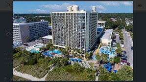 Un hotel con diversi edifici, una grande area piscina e un parcheggio.