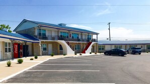 A motel with a blue roof, a Coca-Cola sign, and a parking lot. - Horse Cave Motel (Horse Cave)