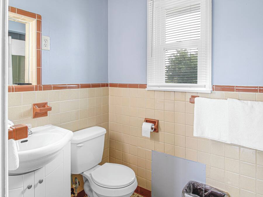 A bathroom with a sink, toilet, and window.