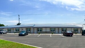 A building with a blue roof, multiple parking spaces, and a flag. - Horse Cave Motel (Horse Cave)