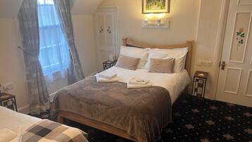 A neatly made bed with a checkered blanket, a bedside table with a lamp, and a framed picture above the bed.