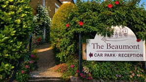 Ein Schild mit der Aufschrift 'The Beaumont Car Park Reception' und einem Weg zu einem Gebäude.