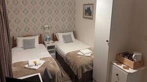 Ein Hotelzimmer mit zwei Betten, einem Nachttisch mit Lampe, einem Kleiderschrank und einem kleinen Tisch mit Tablett.