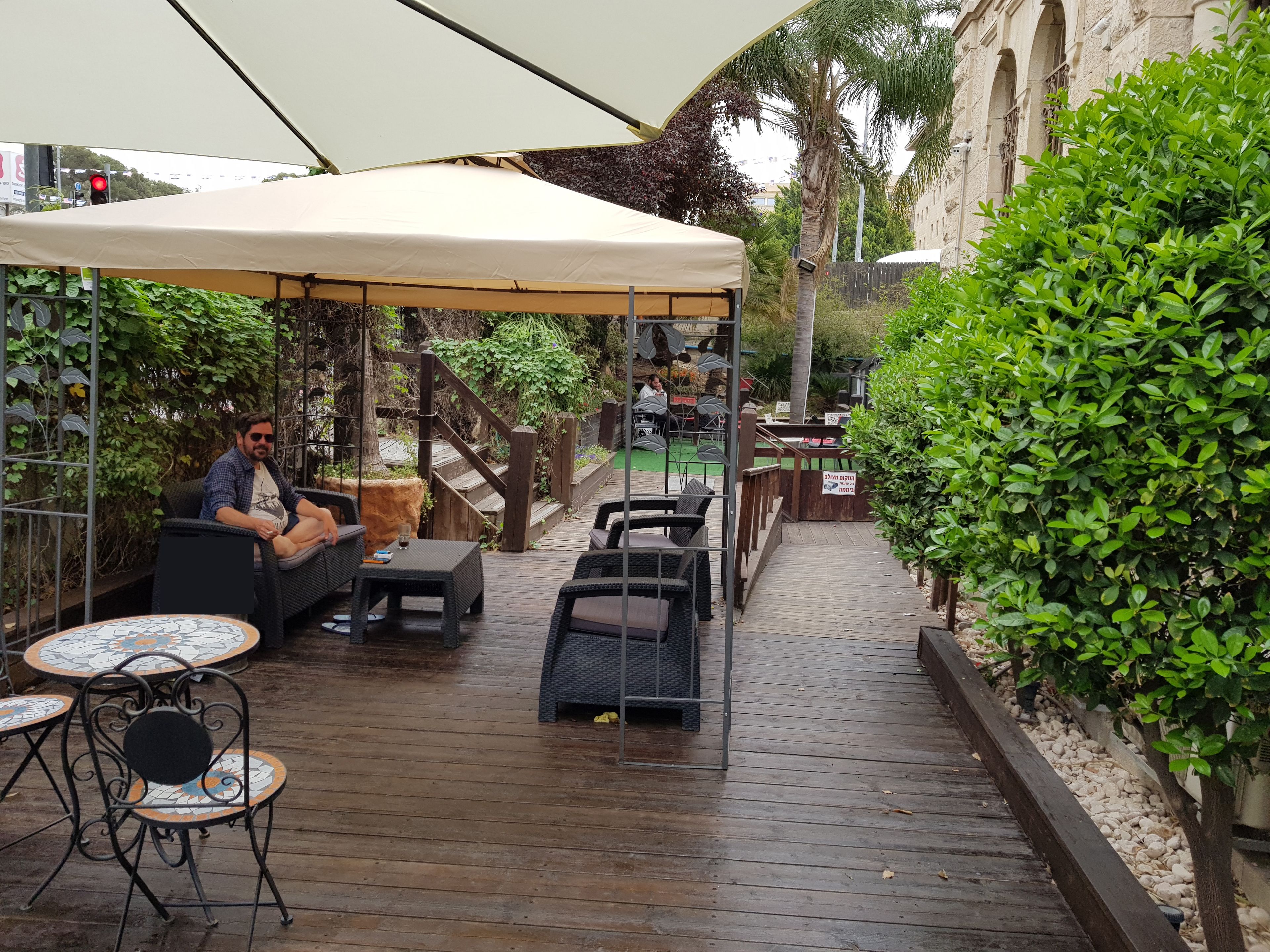 An outdoor patio area with wooden flooring, wicker furniture, and a covered seating area.