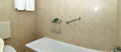 A bathroom with a bathtub, a toilet, and a shelf with toiletries.