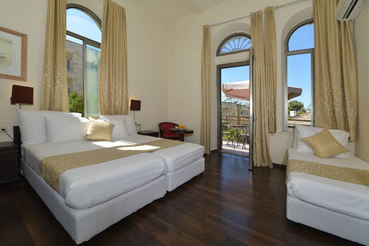 Quarto de hotel com duas camas, varanda e vista para a cidade.