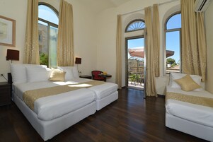 Habitación de hotel con dos camas, un balcón y vistas a la ciudad.