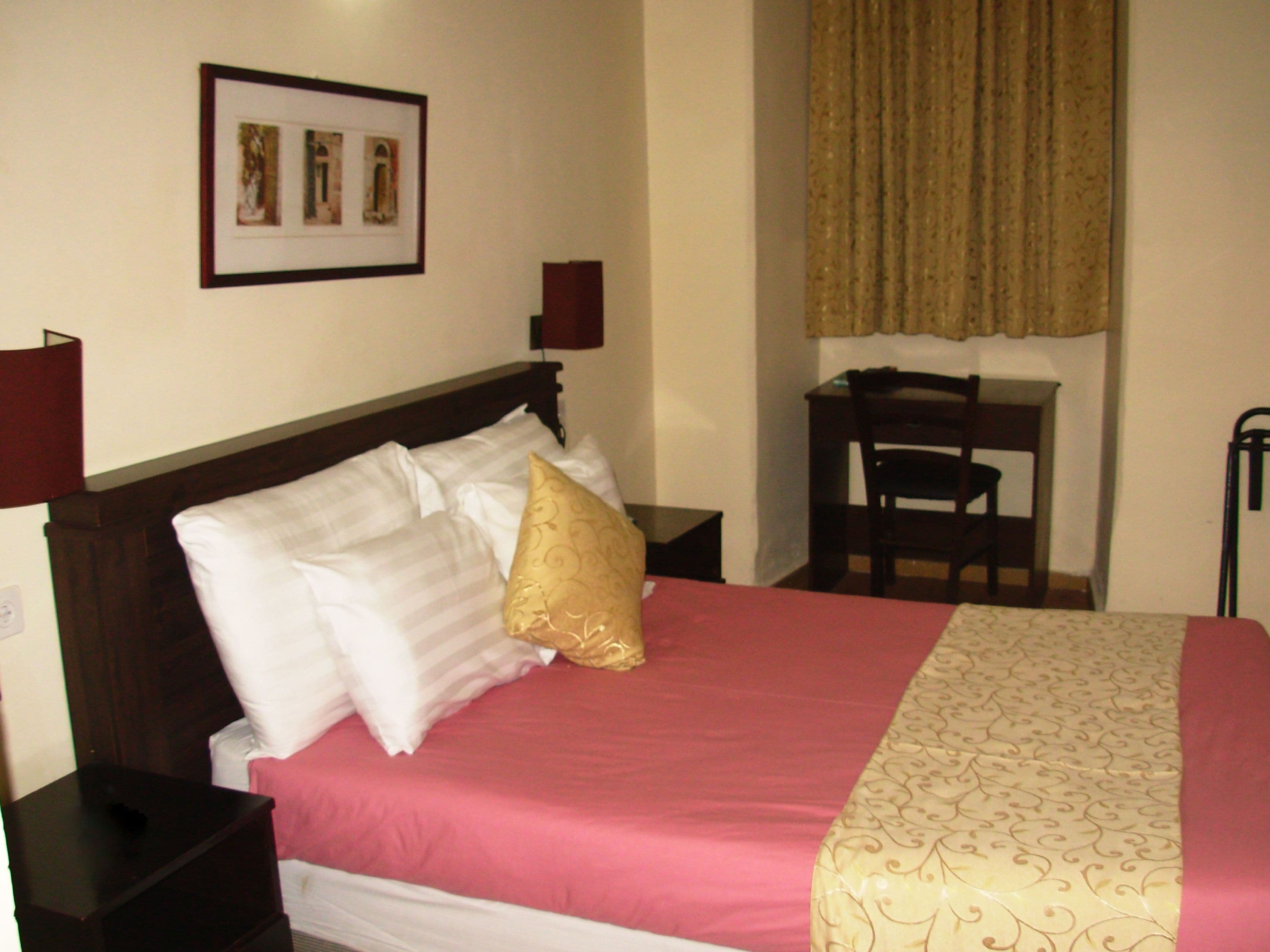 A hotel room with a bed, a desk, and a chair.