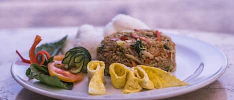 A plate of food with rice, vegetables, and a rolled omelette.