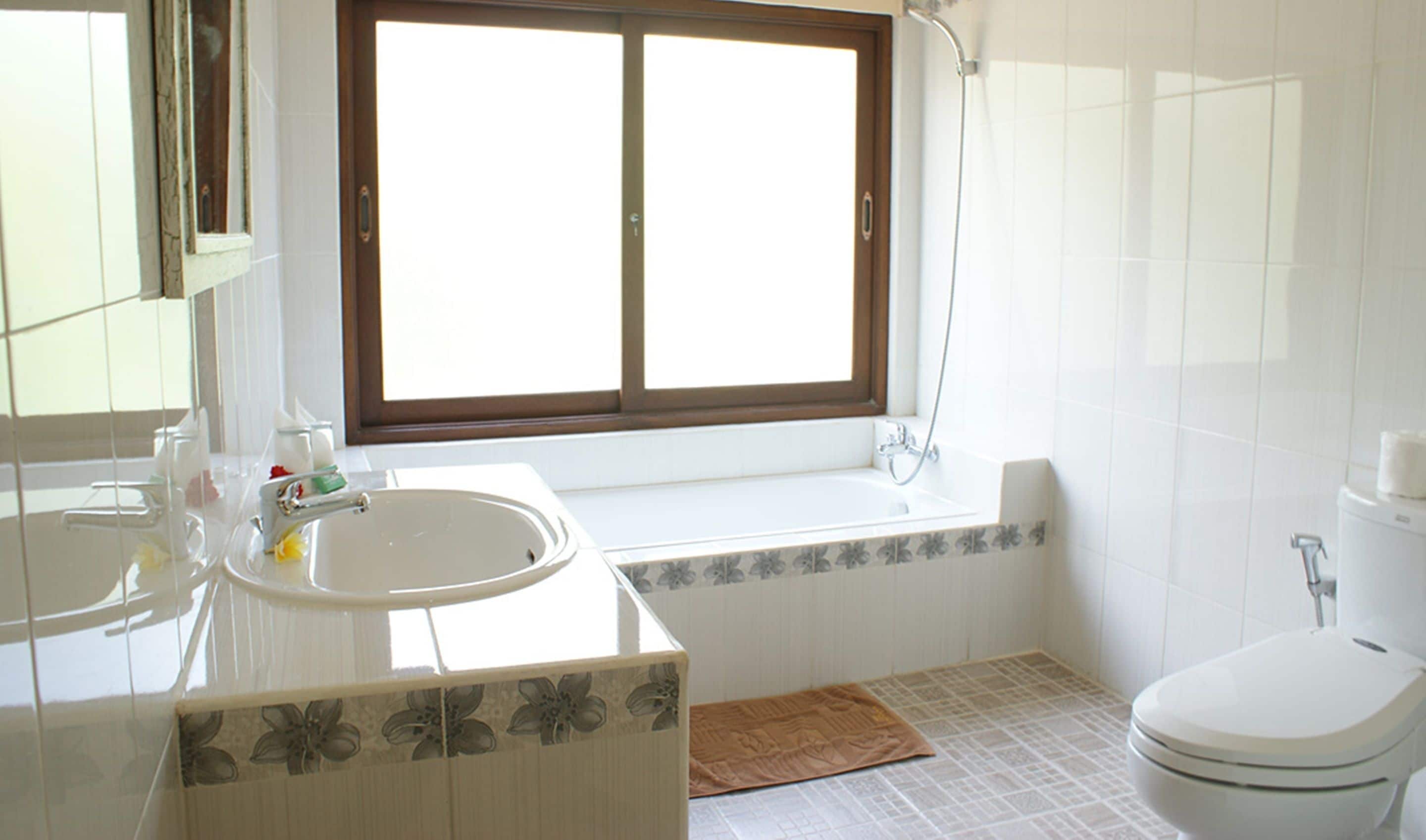 A bathroom with a large window, a sink, a toilet, and a shower.