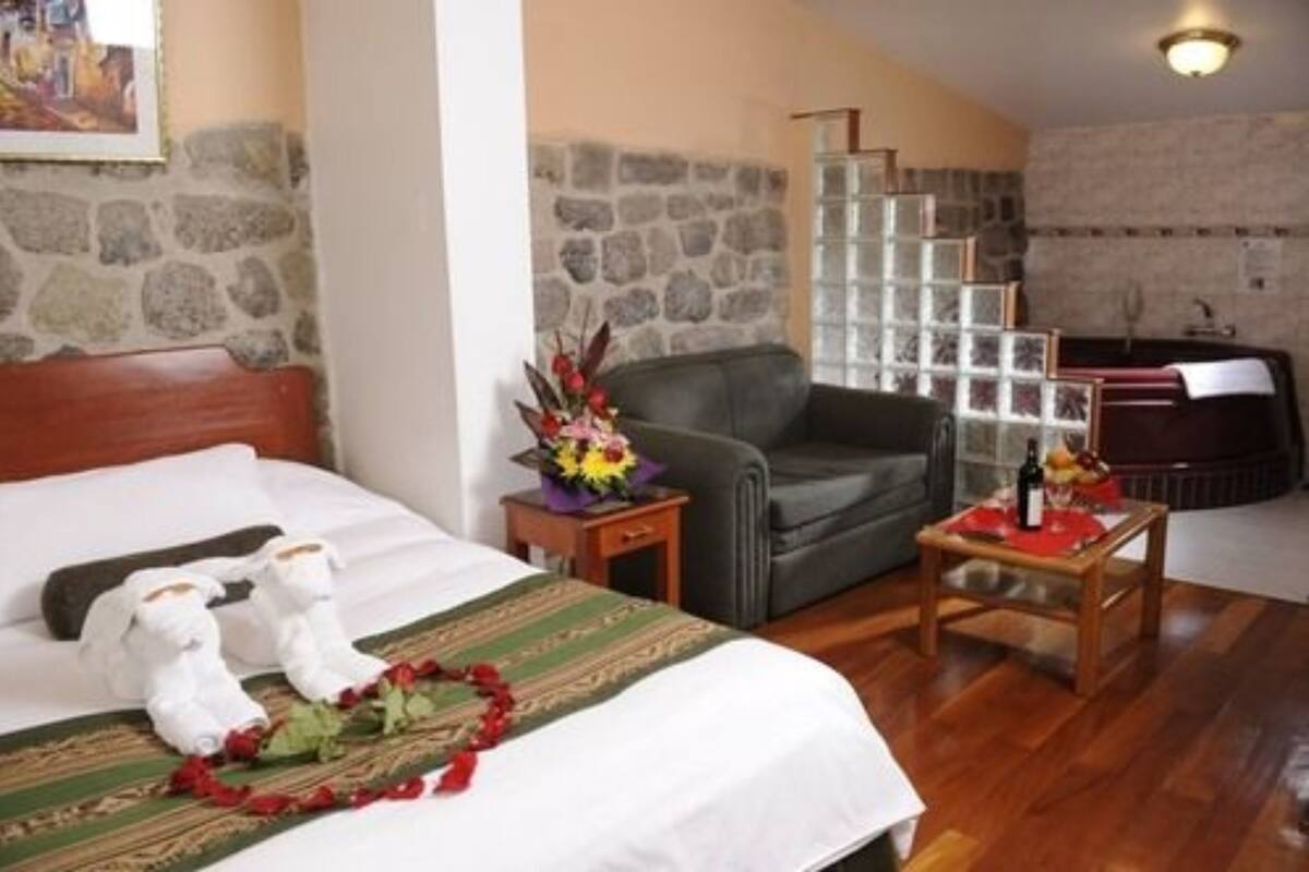 A hotel room with a bed, a sofa, a small table, and a decorative wall with a stone pattern.