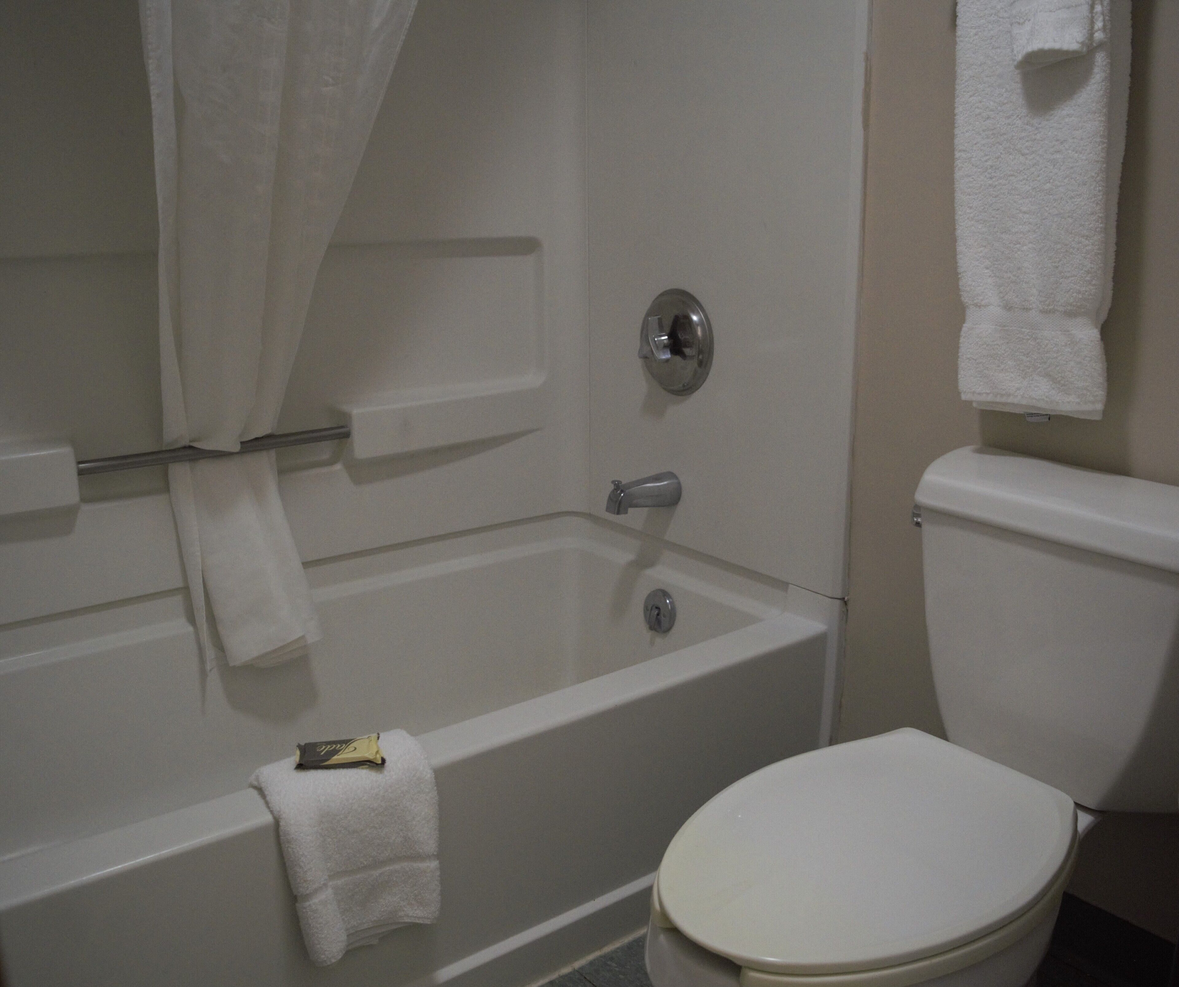 A bathroom with a bathtub, toilet, and a towel rack.