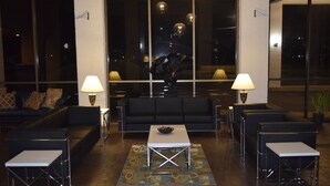 A modern lobby with a black sofa, two white tables, and a patterned rug. - The Landmark Inn (Hartsville)