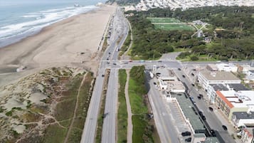 An aerial view of a coastal road with a beach on one side and a residential area on the other.