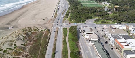 An aerial view of a coastal road with a beach on one side and a residential area on the other.