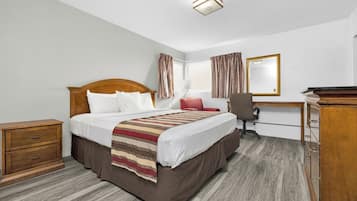 Habitación de hotel con una cama de madera, un escritorio, una silla y una cómoda.