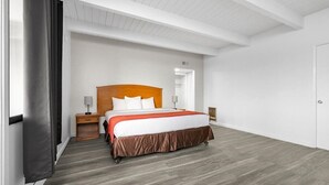 A modern hotel room with a wooden headboard bed, a nightstand with a lamp, and a large window with curtains. - Motel 6 San Francisco, CA – Great Highway (San Francisco)