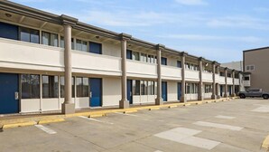 A row of single-story buildings with a uniform facade, featuring a series of windows and doors, and a parking lot in front. - Motel 6 San Francisco, CA – Great Highway (San Francisco)