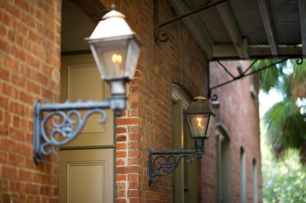 A brick building with a door and two wall-mounted lantern-style lights.