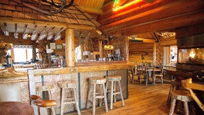 A rustic wooden interior with a bar area, wooden stools, and a fireplace. - Hatchet Resort (Moran)