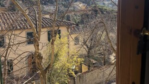 A view through a window of a building with a tiled roof, bare trees, and a hillside in the background. - Hotel Bellavista Impruneta (Impruneta)