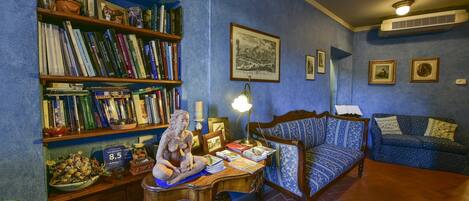 A cozy room with a wooden desk, a blue sofa, and a bookshelf filled with books.