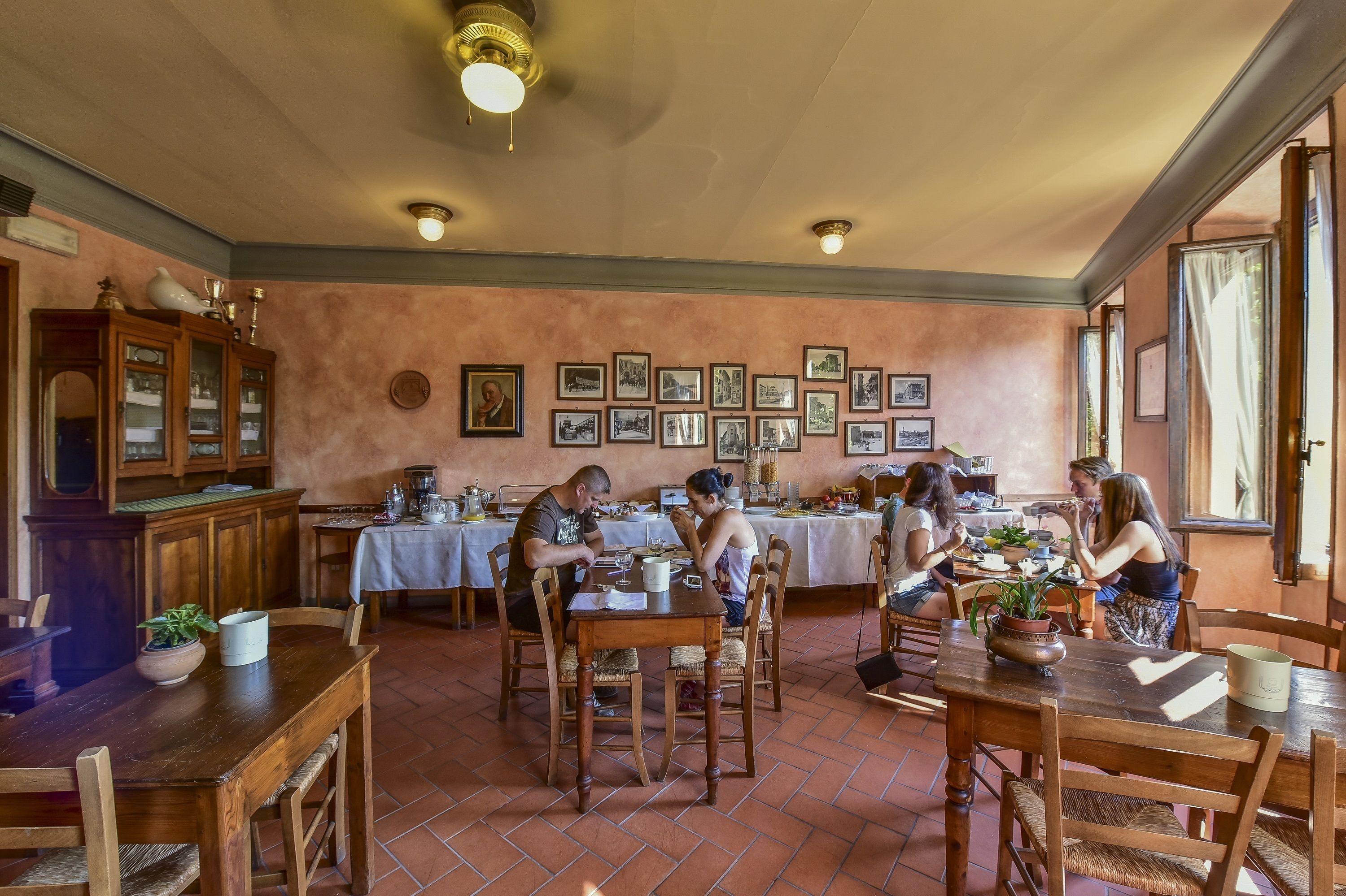 A dining area with wooden tables and chairs, a buffet setup, and framed pictures on the walls.