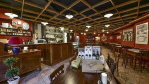 A restaurant interior with wooden beams, a bar area, and tables with wine bottles. - Hotel Bellavista Impruneta (Impruneta)