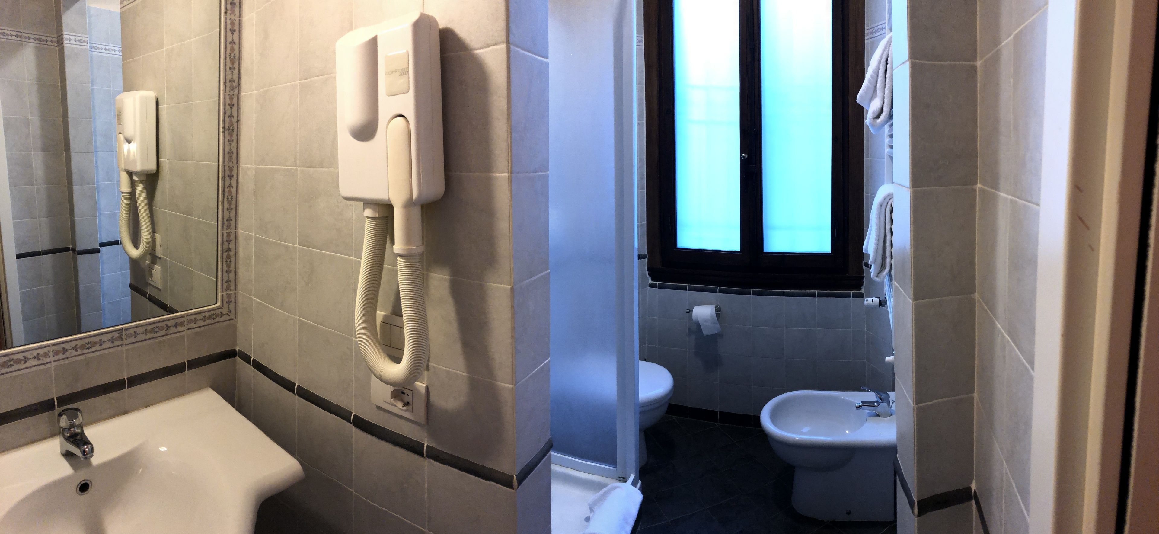 Un baño con lavamanos, inodoro, bidé y un secamanos instalado en la pared.