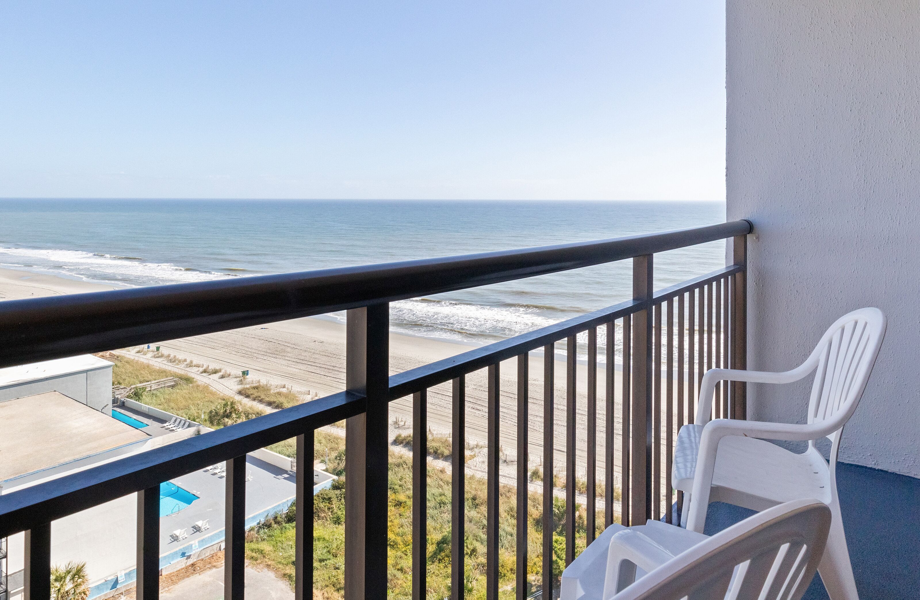 A balcony with a view of the beach and ocean.