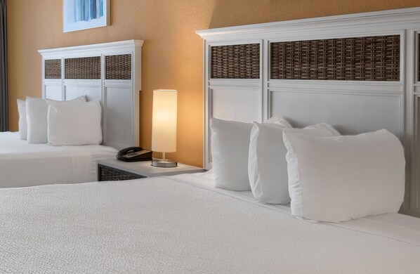Habitación de hotel con dos camas, una lámpara de noche, un teléfono y una obra de arte colgada en la pared.