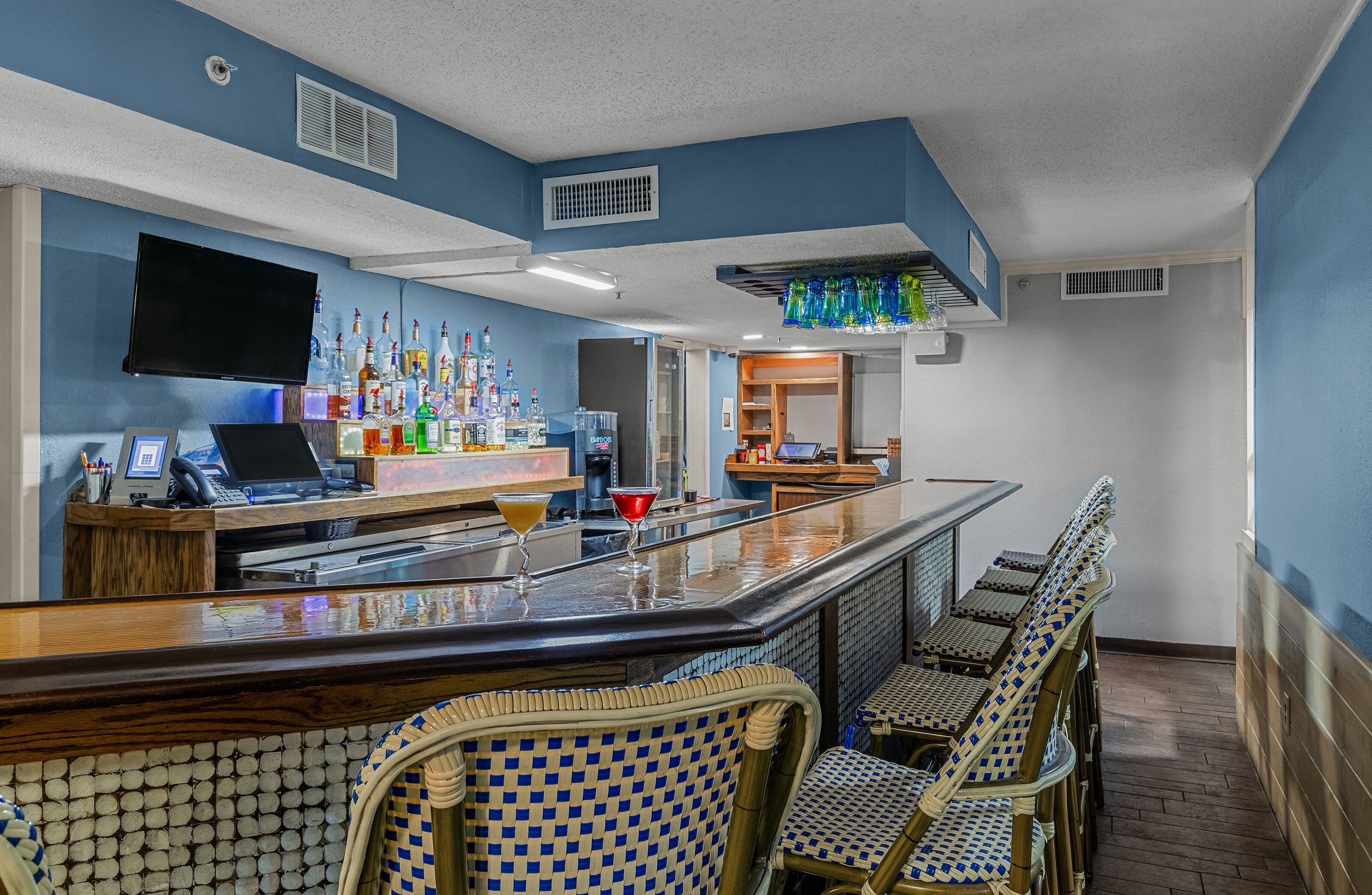A bar area with a counter, bar stools, and a television mounted on the wall.