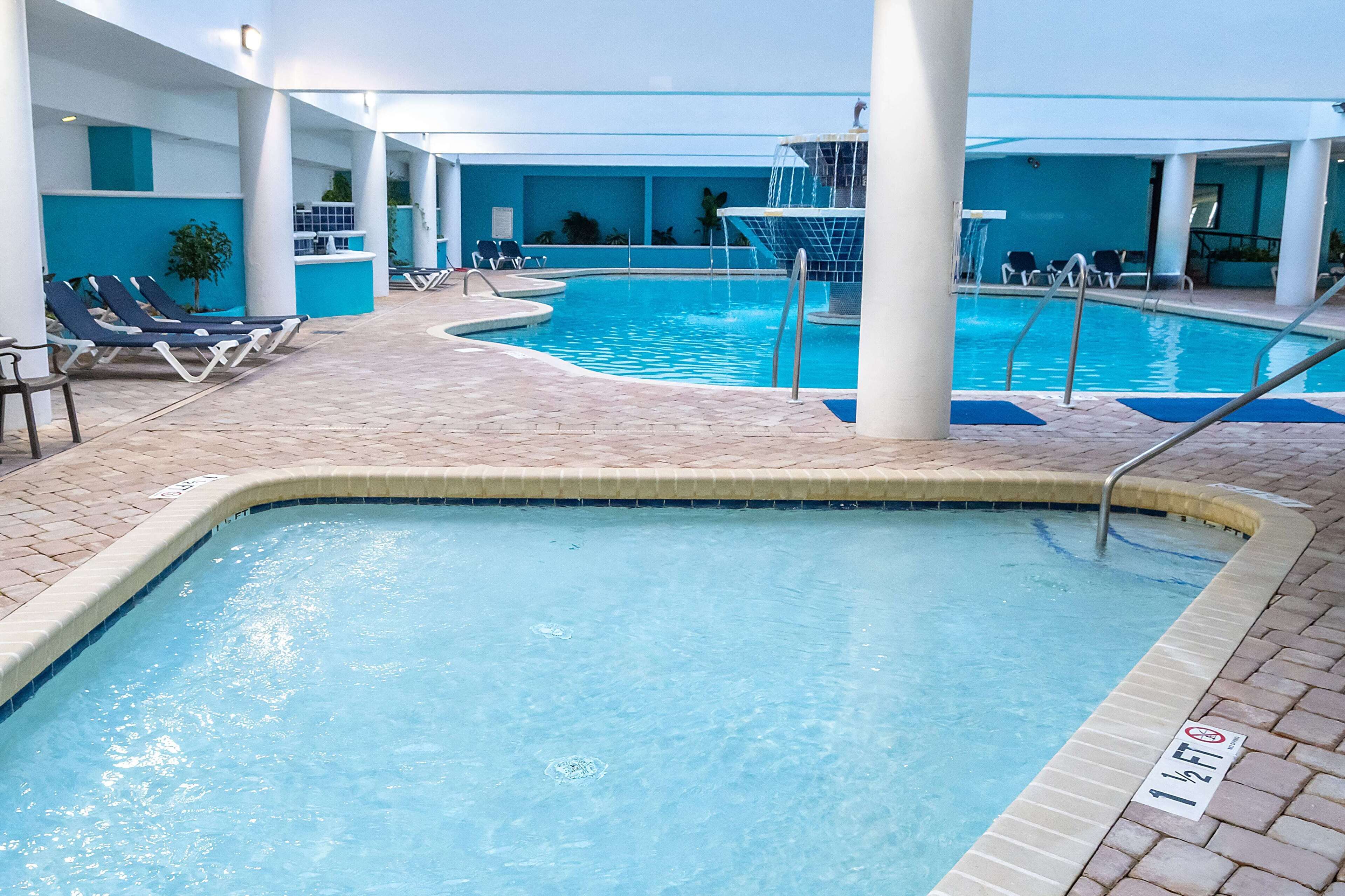 A swimming pool with lounge chairs and a water slide.