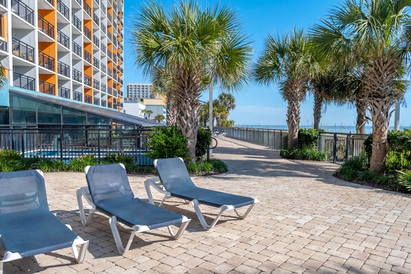 A beachfront hotel with a pool, palm trees, and lounge chairs. - Landmark Resort (Myrtle Beach)