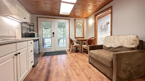 A compact living space with a kitchenette, a dining area, and a seating area with a sofa. - Aloha Junction Guest House (Volcano)