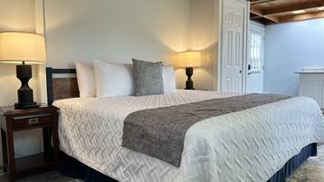 A bedroom with a bed, two bedside tables with lamps, a door, and a window.