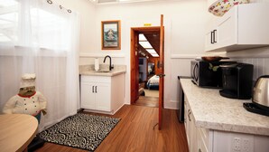 A modern kitchen with white cabinets, a wooden countertop, and a skylight. - Aloha Junction Guest House (Volcano)