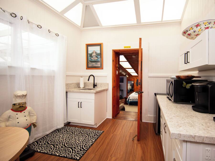 A modern kitchen with white cabinets, a wooden countertop, and a skylight.
