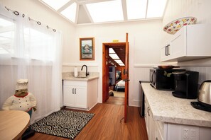 A modern kitchen with white cabinets, a wooden countertop, and a skylight. - Aloha Junction Bed and Breakfast (Volcano)