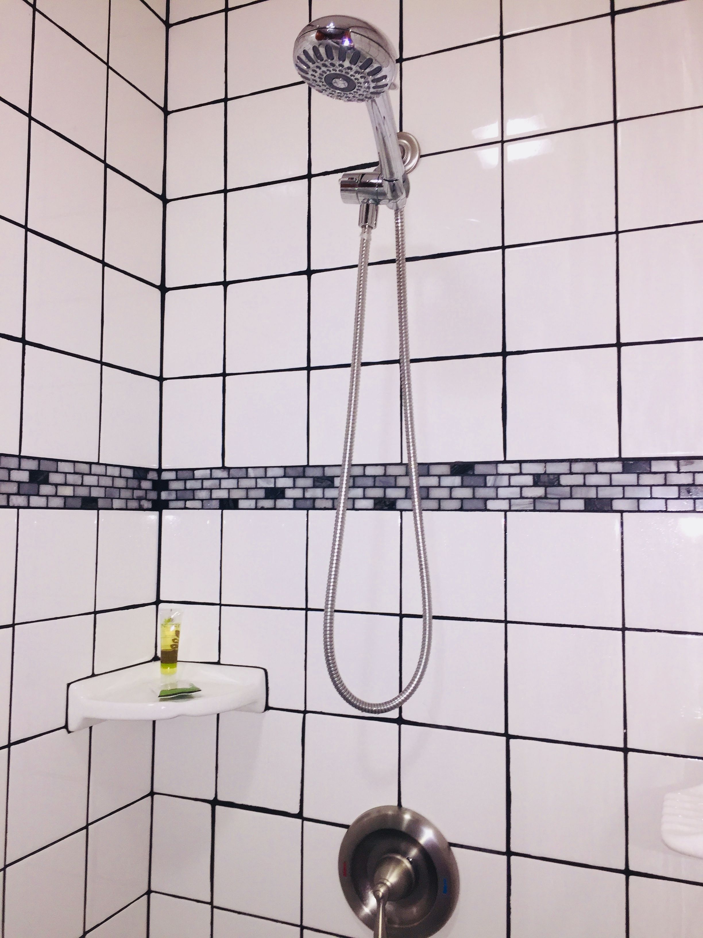 Eine Dusche mit Duschbrause und Wandarmatur.