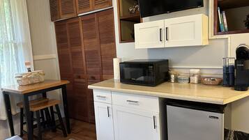 A compact kitchen with a microwave, coffee maker, and a small refrigerator.